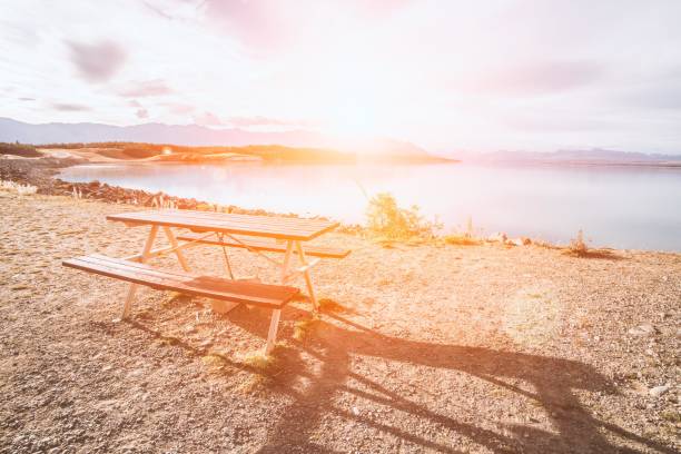 Wooden picnic table on a lake shore at sunset