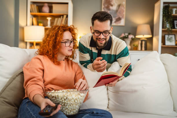istock cheerful couple enjoy together on sofa with book and popcorn 2193125016