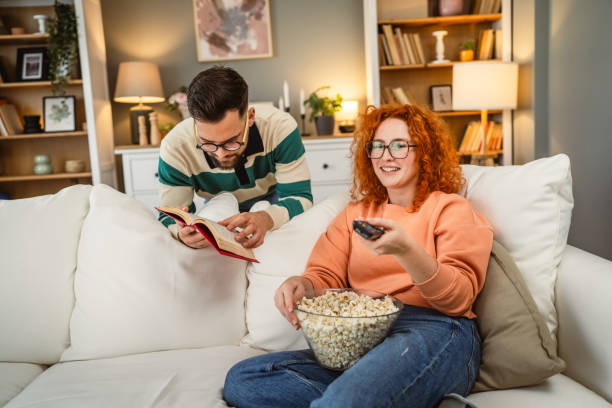 istock cheerful couple enjoy together on sofa with book and popcorn 2193125127