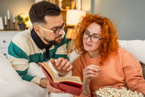 istock cheerful couple enjoy together on sofa with book and popcorn 2193125531