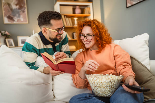 istock cheerful couple enjoy together on sofa with book and popcorn 2193125862