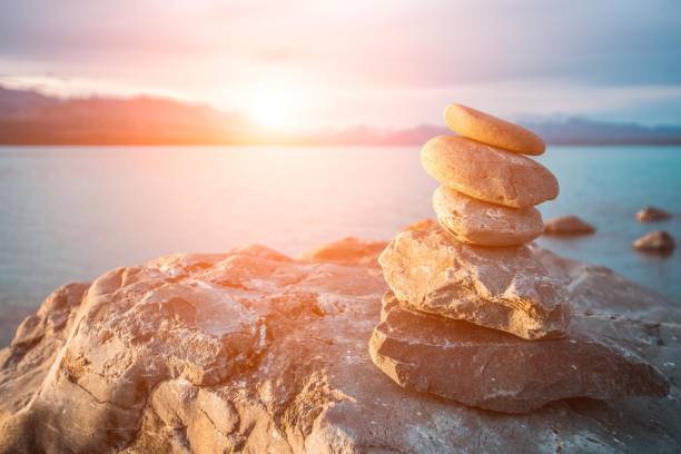 Stack of stones on the beach with blurred lake and sunset in the background