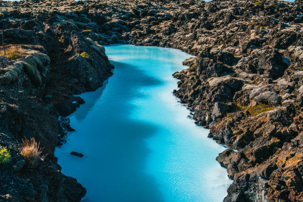 A serene body of blue water flows gracefully between rocky formations, showcasing the beauty of nature's untouched landscape. The tranquil scene invites viewers to explore.