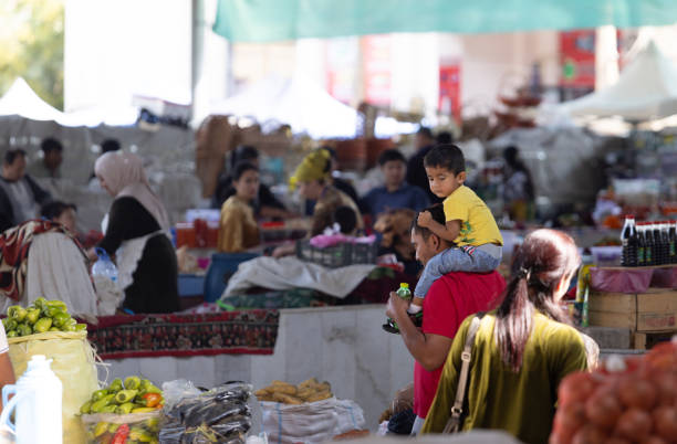 Samarkand, Uzbekistan October 1 2024: man and his son have piggyback ride and walk in the market. the hawker sell the fruits in Siab bazaar. Siab bazaar is main bazaar in Samarkand