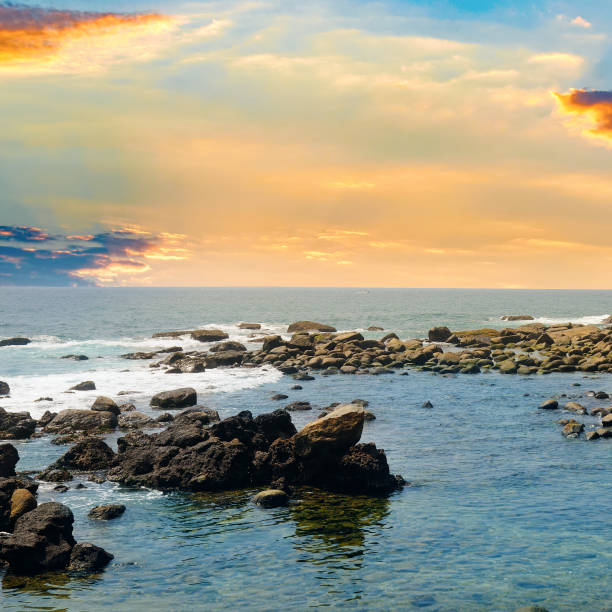 Seascape with beautiful waves, rocky shore and bright sunrise. Concept - vacation and travel.