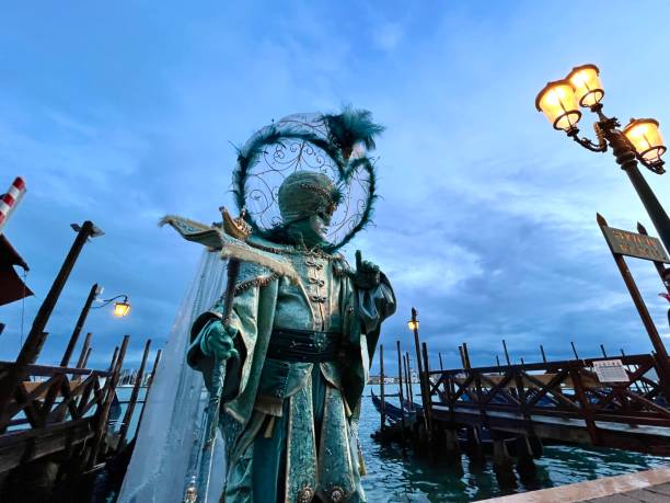 Couple of silver masks in beautiful green and turquoise costumes at carnival in Venice, Italy.