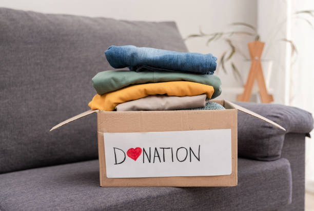 istock Used clothes are awaiting donation in a cardboard box on a sofa 2193138661
