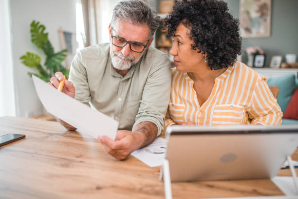 istock A diverse couple are working together to calculate their monthly spending and income while worrying about the high cost of living, sitting together at a dining table 2193139183