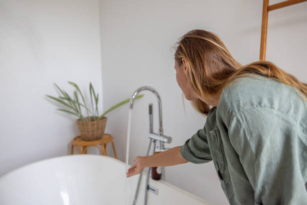 istock Woman Testing Water Temperature in a Modern Bathroom 2193140462