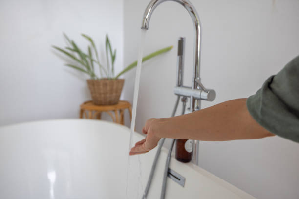 Woman Testing Water Temperature in a Modern Bathroom
