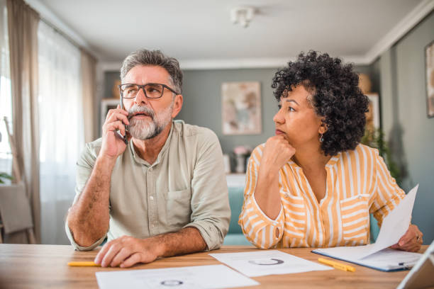 istock Multiracial woman sitting next to man making a phone call with a customer support representative 2193143158