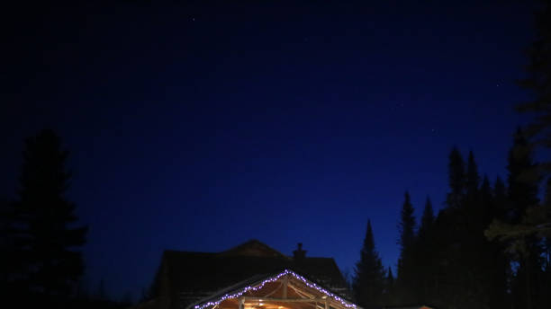 Christmas Card Night Sky Treeline and Cabin with Lights Background with Copy Space