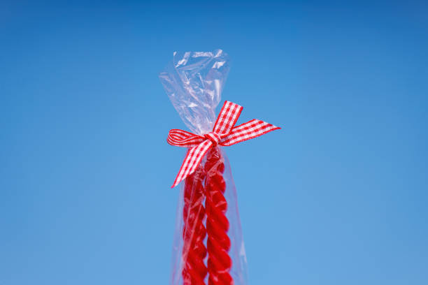 vibrant red and white bow atop a clear plastic package containing two red spiral candles. Perfect for festive occasions and celebrations