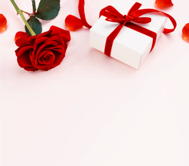 istock Red rose and gift box top view on soft pink empty space background. Valentine's card, romantic holiday frame. Birthday gift. 2193147376