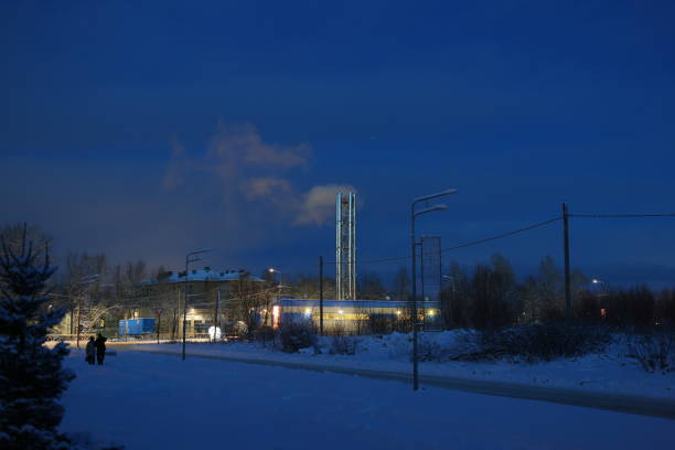 On a chilly winter evening, an industrial site is surrounded by pristine white snow beneath a dusky sky