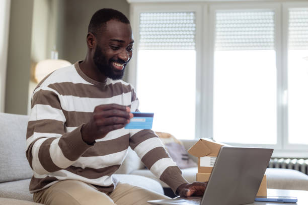 istock Man shopping online with a credit card using a laptop at home 2193152469