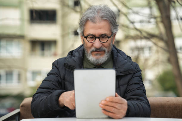 istock Elderly Man Reading on a Tablet Outdoors 2193153251