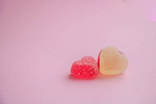 Multicolored gummy hearts on pink background