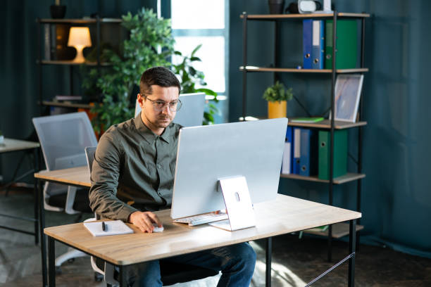 istock Young and confident businessman working in a modern office. Business man using computer. 2193161335