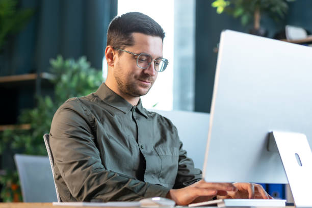 istock Photo portrait of smiling guy working on desktop pc at table indoors 2193161359