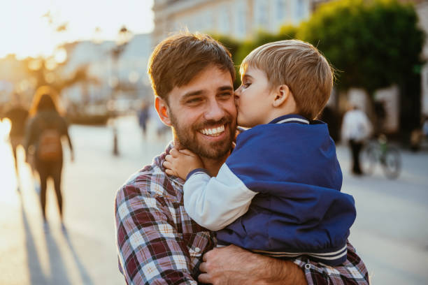 istock Single father spending sunny spring afternoon with his young son. Emotional hugging and kissing in summer sunset between father and son 2193168701