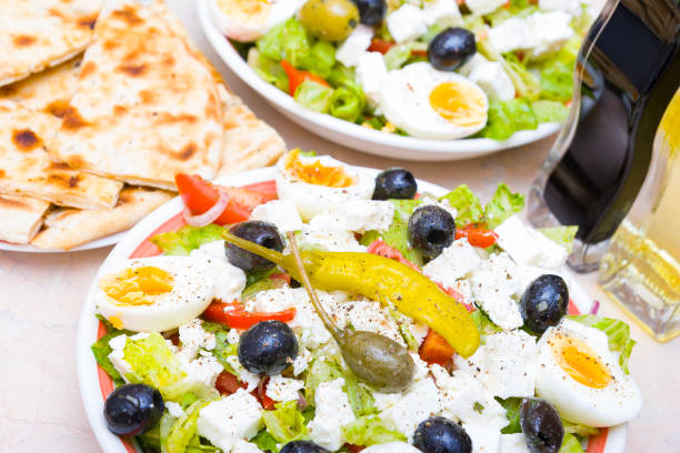 Bowls of Greek salad, naan bread and vinegar and oil bottles.