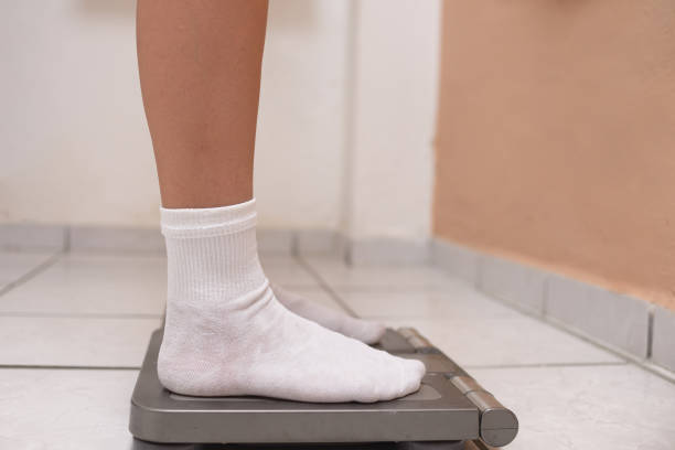 istock Female feet on a weighing scale. Body weight control concept. 2193174599