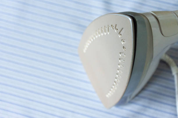 Close up of an iron on a blue striped shrit