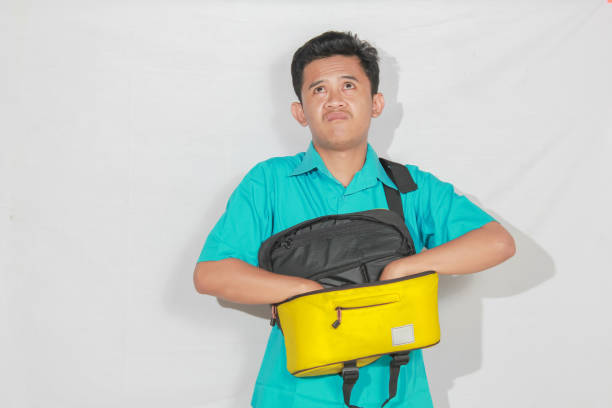 istock Asian man reaching into bag with annoyed expression isolated on white background 2193176729