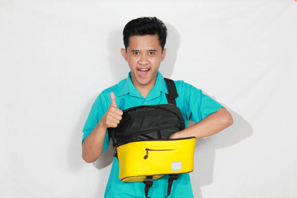 istock Asian man reaching into sling bag giving ok sign with cheerful expression, isolated on white background 2193176735