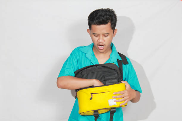 istock Asian man reaching into bag with annoyed expression isolated on white background 2193176736