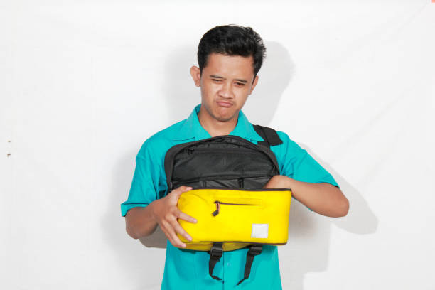 istock Asian man reaching into bag with annoyed expression isolated on white background 2193176759