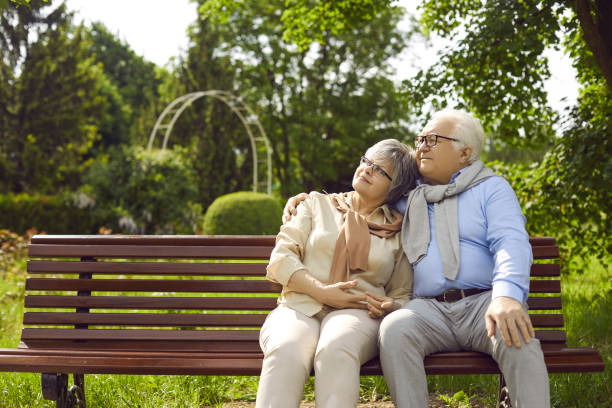 istock Romantic loving senior elderly couple sitting on bench and hugging in park 2193179603