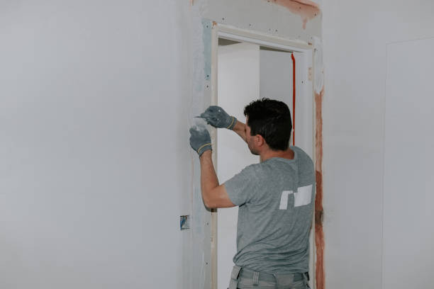 istock One young man covers up the mesh in the doorway with putty. 2193181120