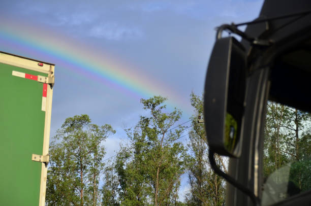 A beautiful colorful rainbow in the sky seen from the highway full of vehicles