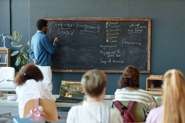 istock Wide Angle View of Class with Black Male Teacher Writing on Blackboard 2193187516
