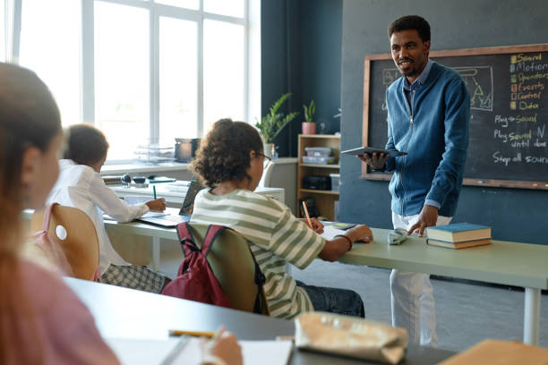 istock Class with Group of Kids in Row Black Teacher Talking 2193187527