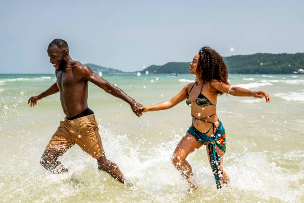 istock Joyful Couple Running Through Ocean Waves on Beach 2193188771
