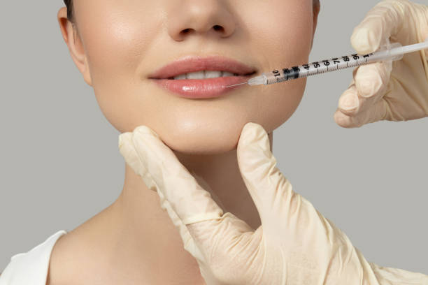 istock A beautiful girl makes an injection in the lips, on a gray background 2193190799