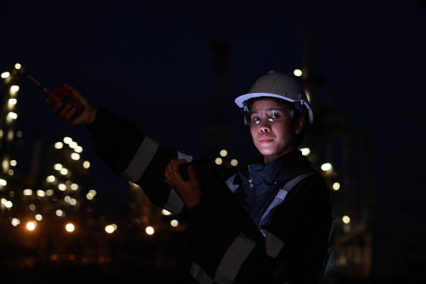 istock Engineer woman using a digital tablet and walkie talkie working late at night in refinery plant on background. 2193192551