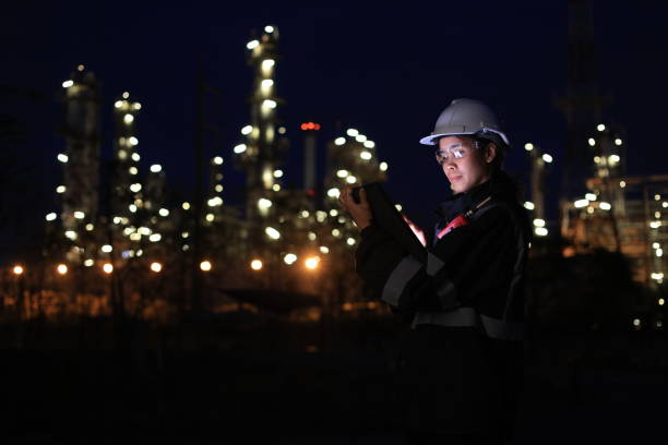 istock Engineer woman using a digital tablet and walkie talkie working late at night in refinery plant on background. 2193192576