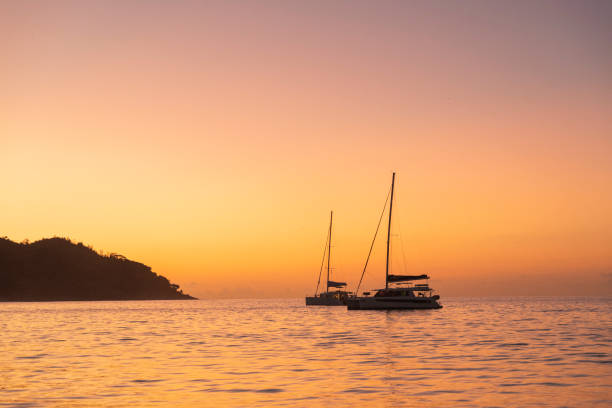 View across tranquil bay to sailboats at sunset
