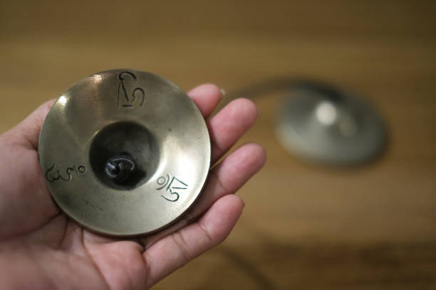 close-up shot of Unrecognizable person holding  Tibetan Tingsha bell. Concept: Tibetan culture, Tingsha bell, meditation tools, sacred sound, spiritual practice, mindfulness, Tibetan traditions, ritual instrument, close-up detail, cultural heritage, tranquility, meditation accessory, ancient wisdom, harmonic tones, spiritual connection.