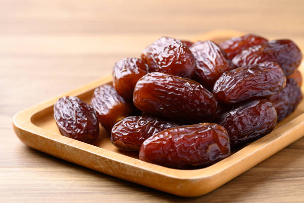 istock Date palm fruit (MedJool) on wooden plate 2193204855