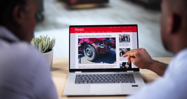 Watching Online News Article On Mobile Phone And Laptop. Electronic Newspaper