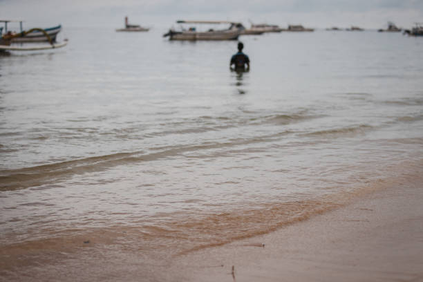 Fisherman is fishing in the ocean at Sanur beach.Bali island - Indonesia.