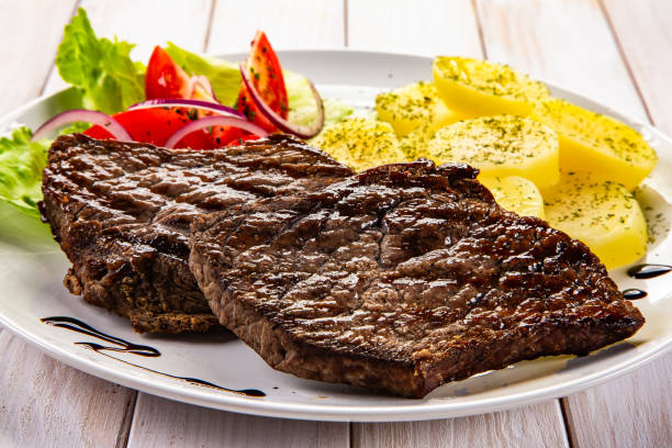 istock Seared beef steaks with boiled potatoes and fresh vegetable  on wooden table 2193209611