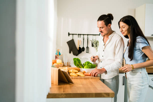 istock A couple prepares fresh ingredients in a bright kitchen, smiling and enjoying their time together while using a tablet for cooking inspiration. 2193209700
