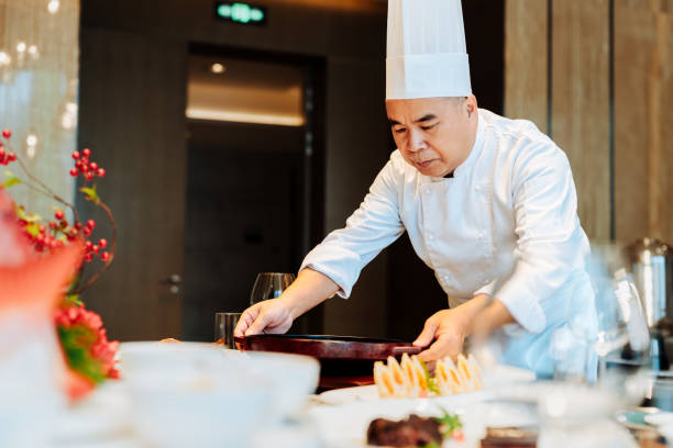 istock Asian senior chef serving meal at table a luxurious private room. 2193214227