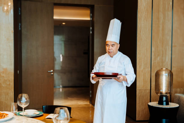 istock Asian senior chef serving meal at table a luxurious private room. 2193214237